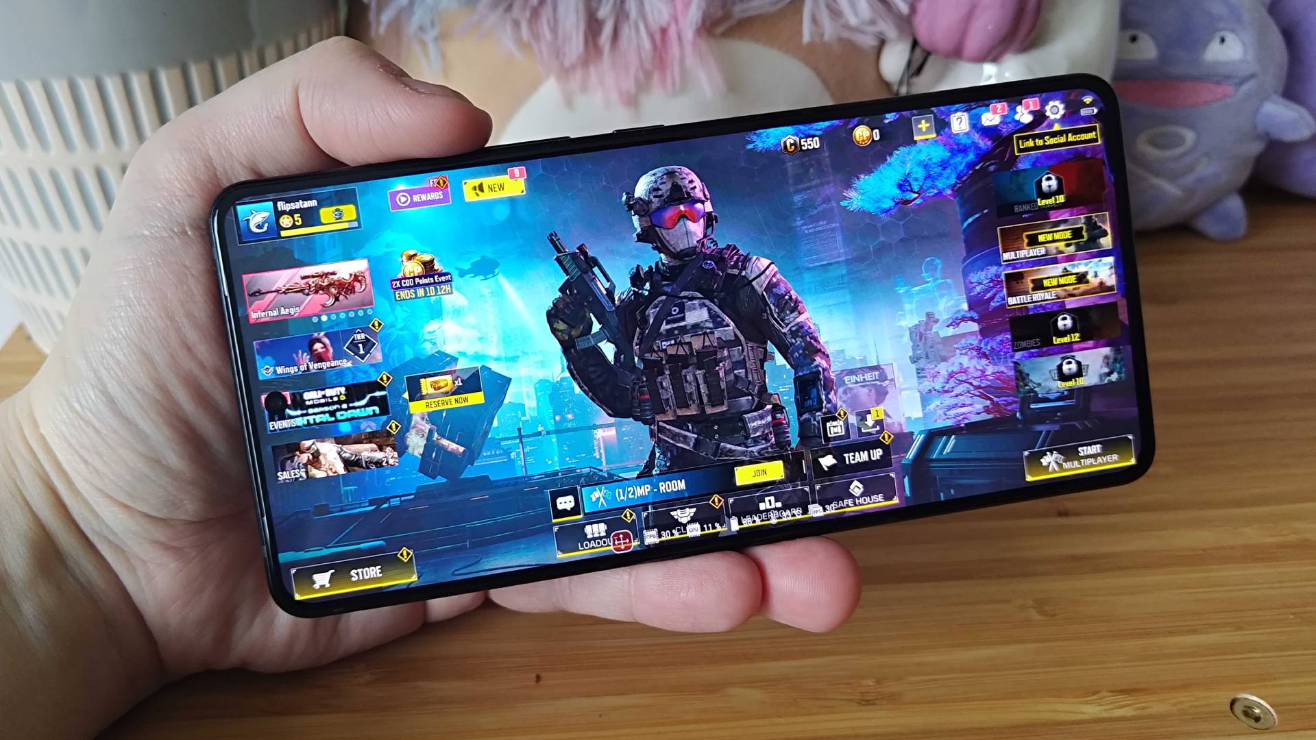 A hand holding a smartphone displaying call of duty gameplay